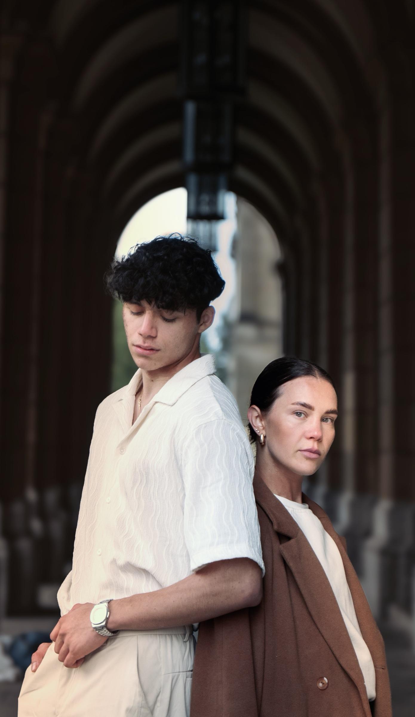 Couple standing back to back beneath stone arches