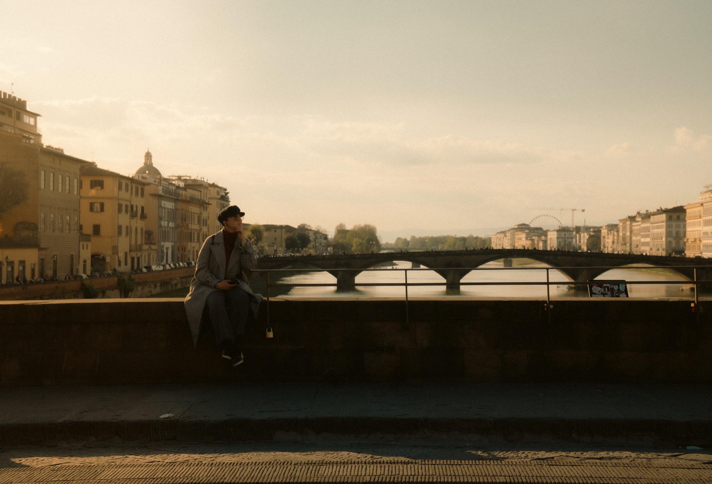 Couple sitting on a bridge in Florence at sunset