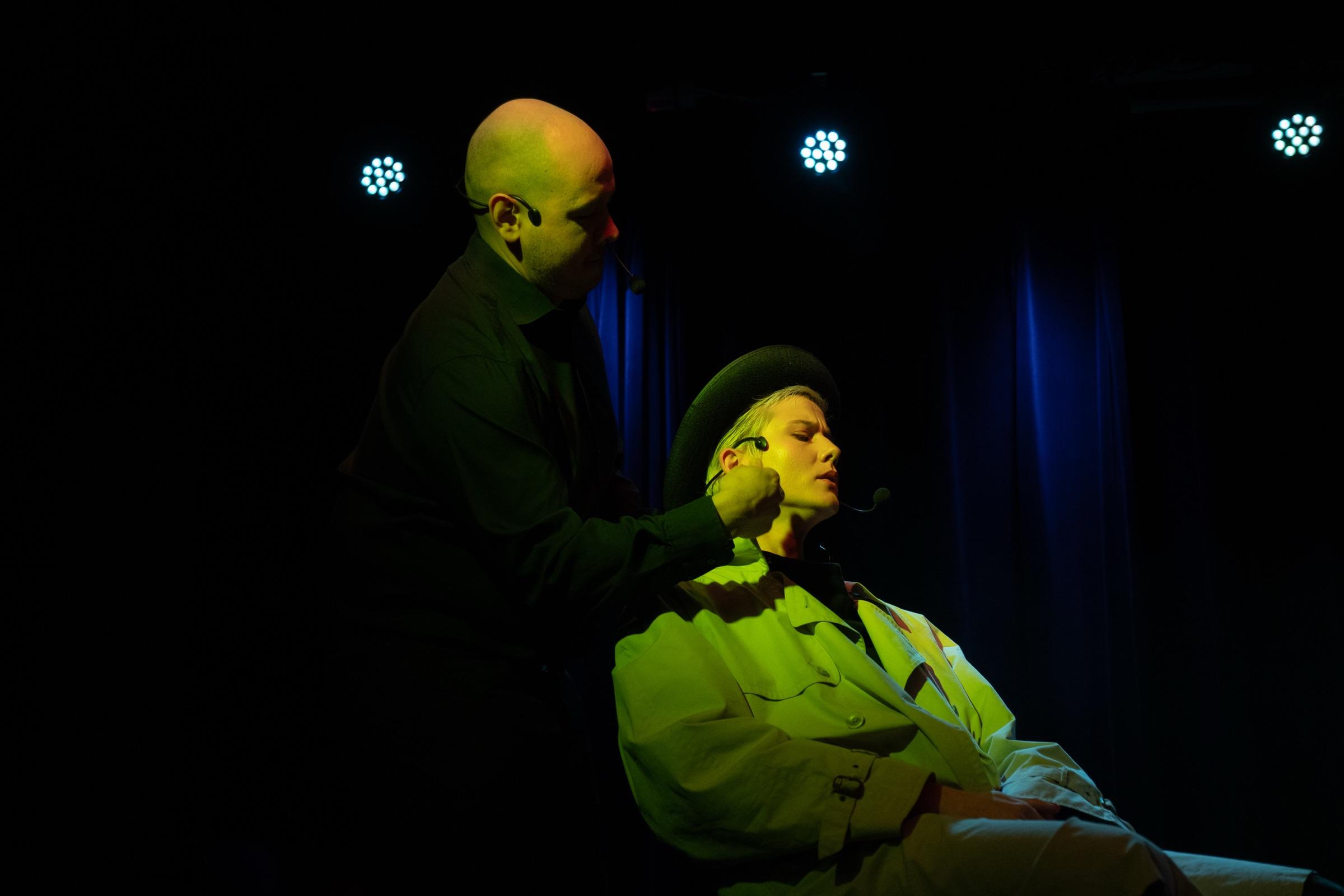 Dramatic two-person improv scene lit in green and gold