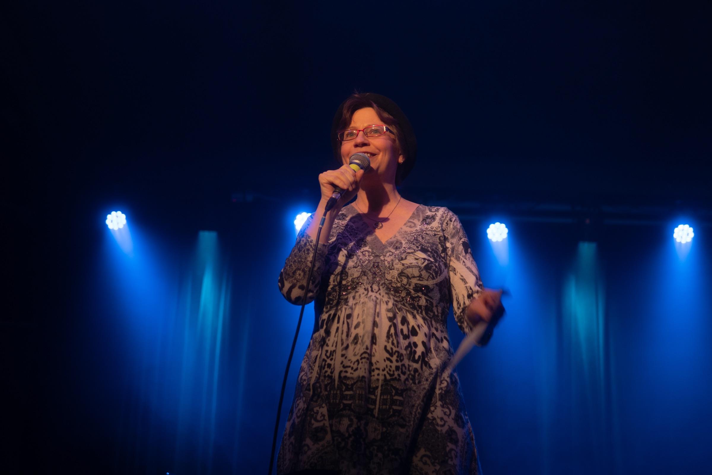 Singer performing into a microphone under blue stage lights