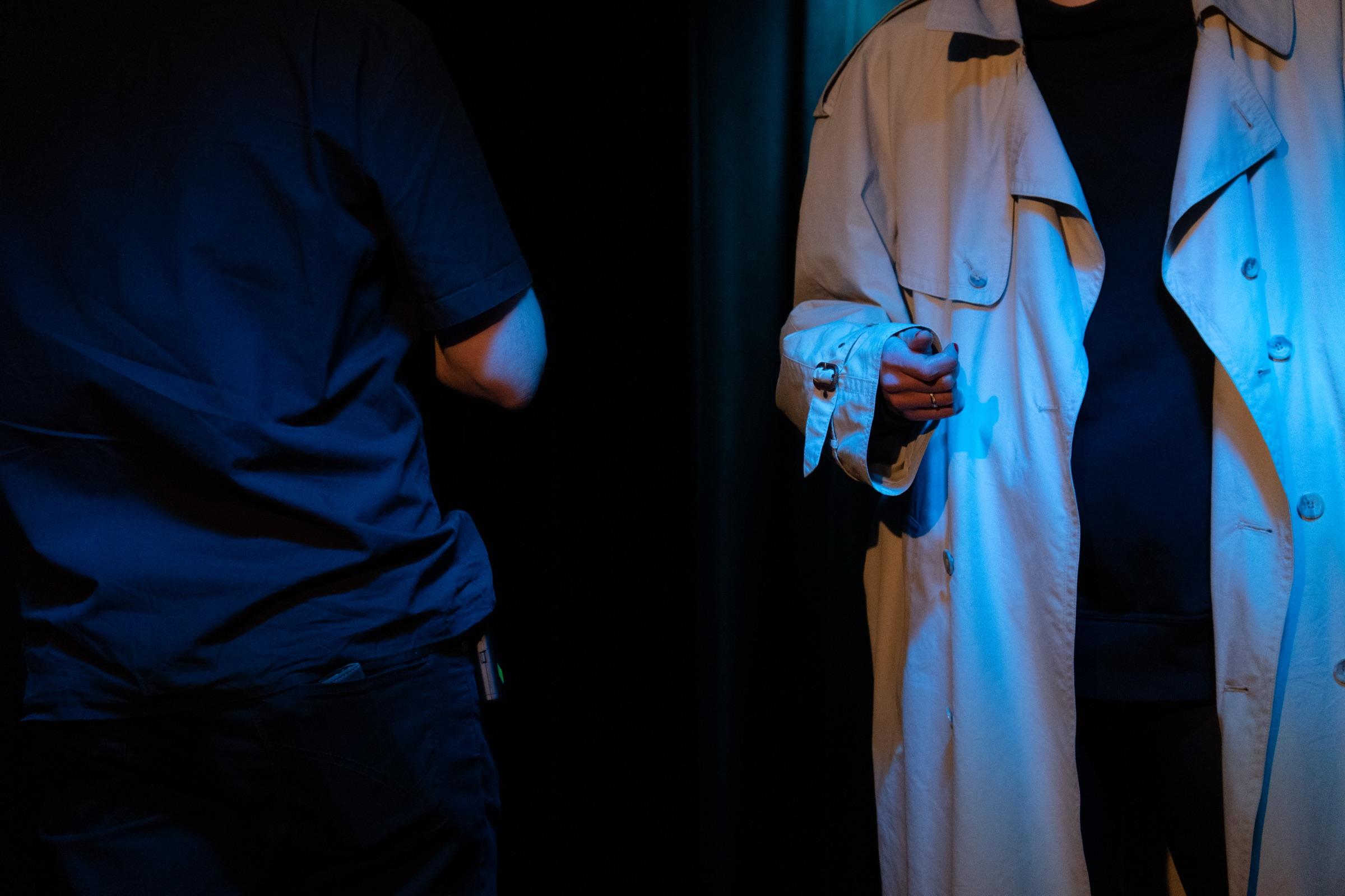 Stage detail of two performers in a noir improv scene
