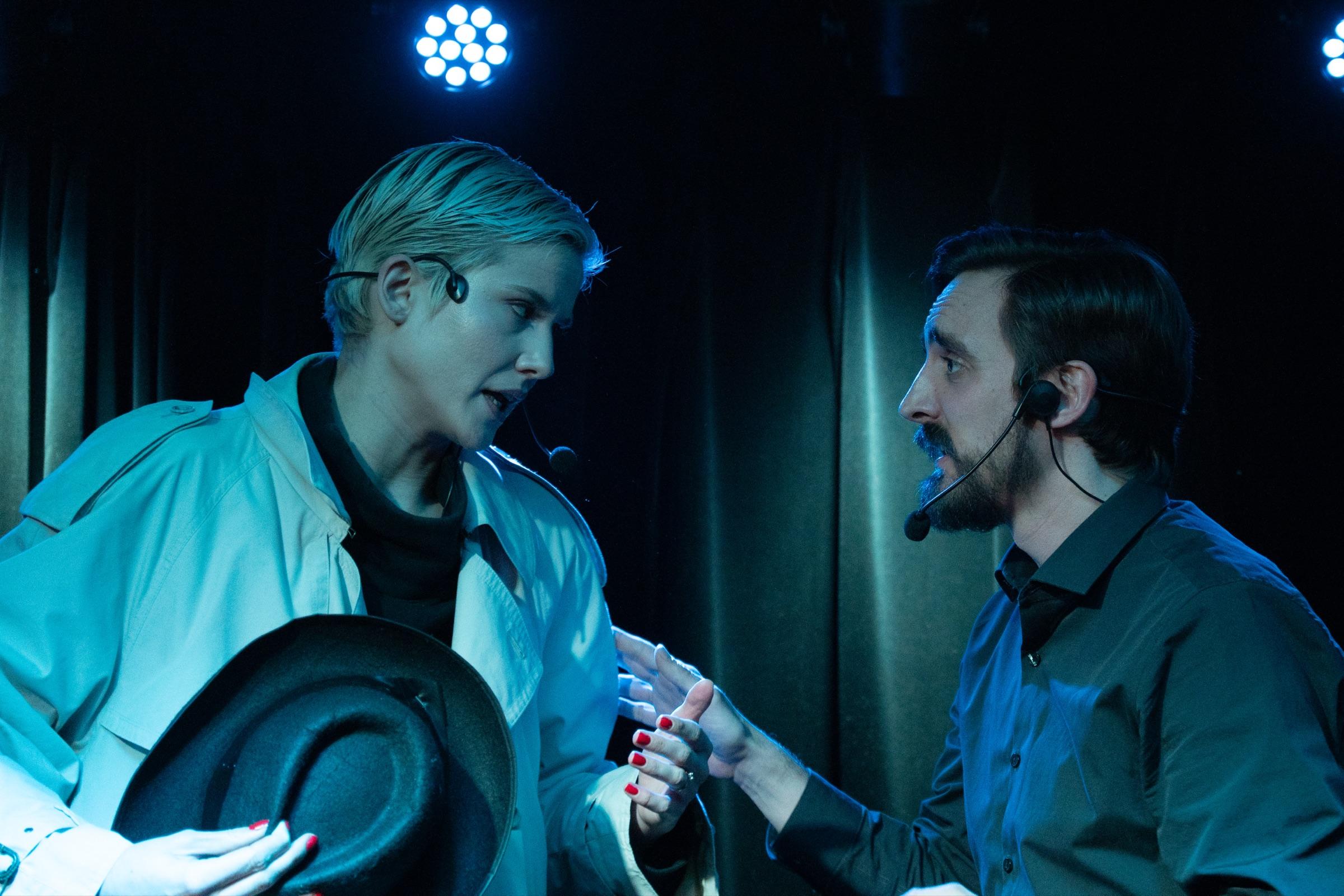 Two improvisers in a tense scene under stage haze