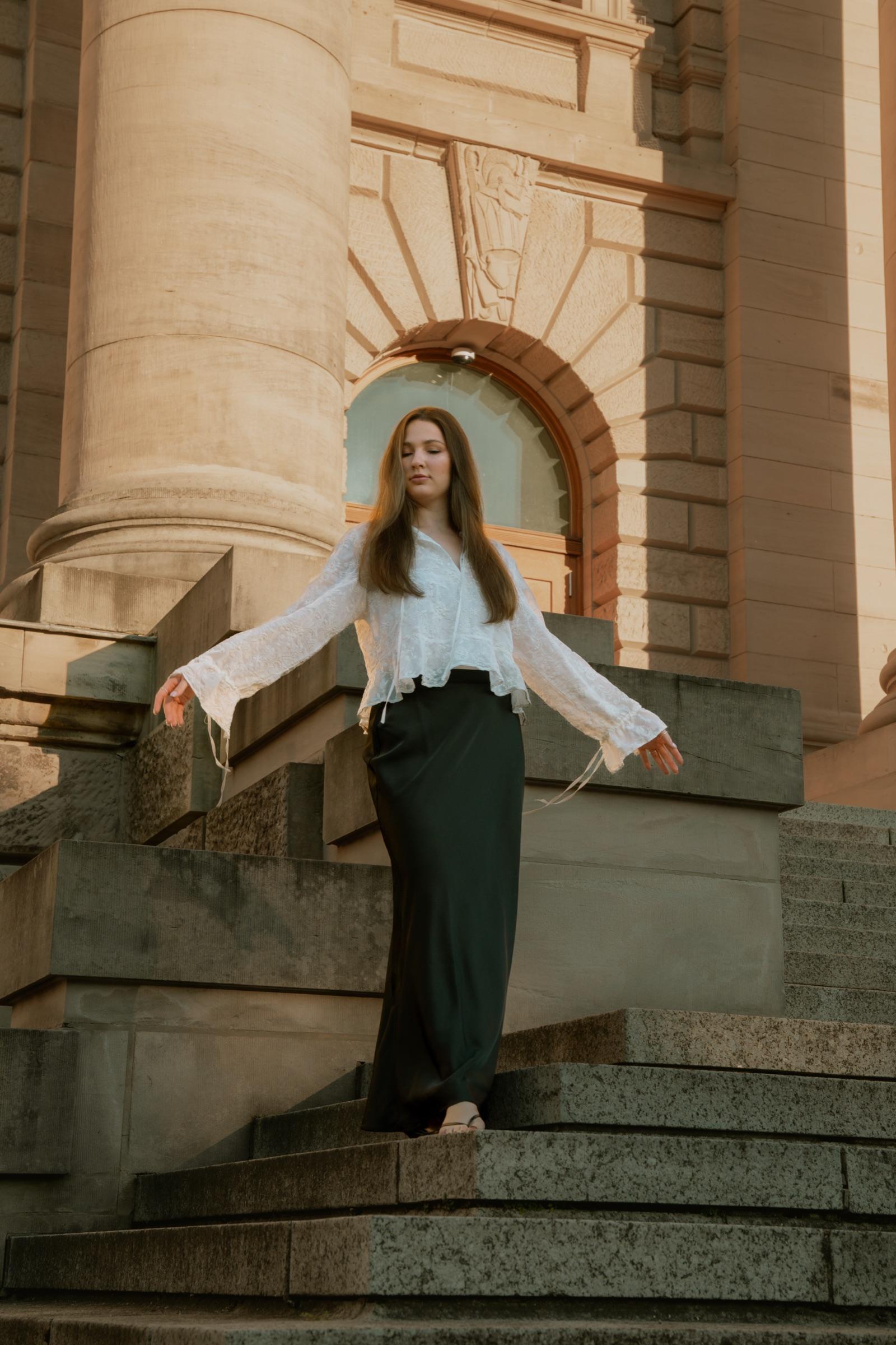 Editorial portrait with arms outstretched on stone steps
