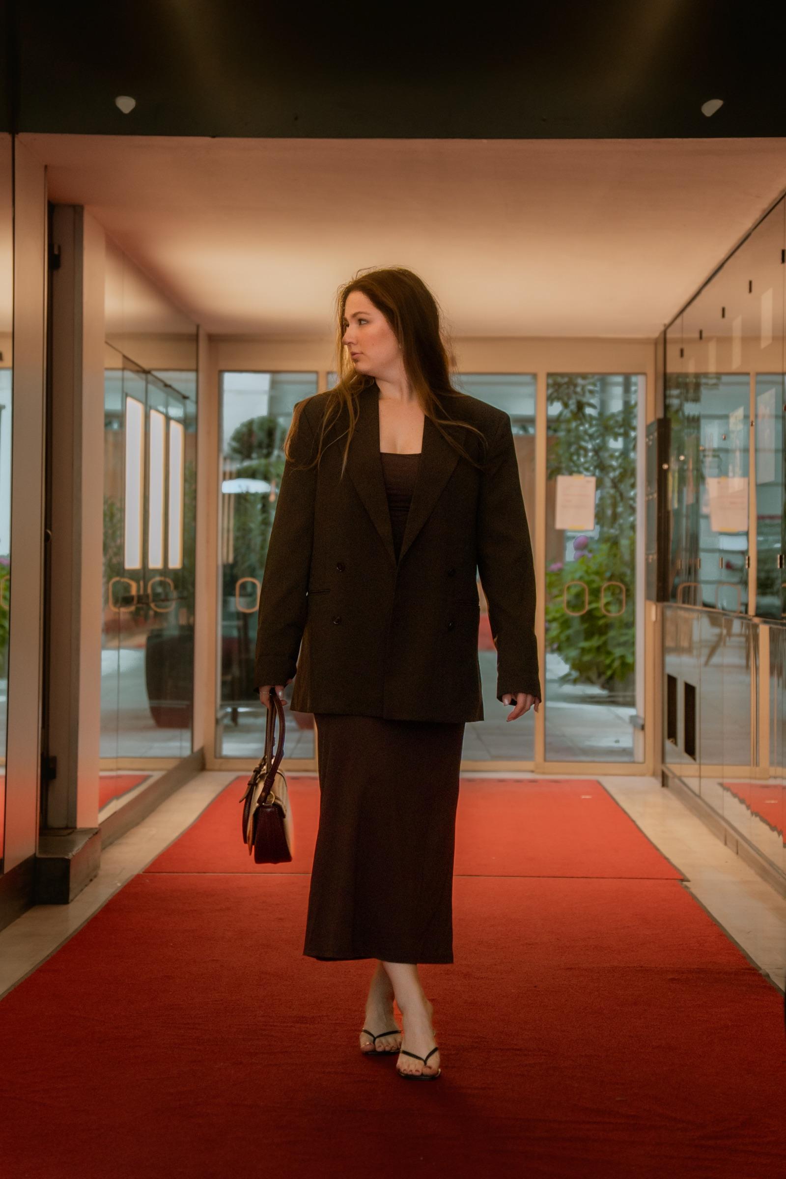 Editorial portrait on a red carpet glancing aside