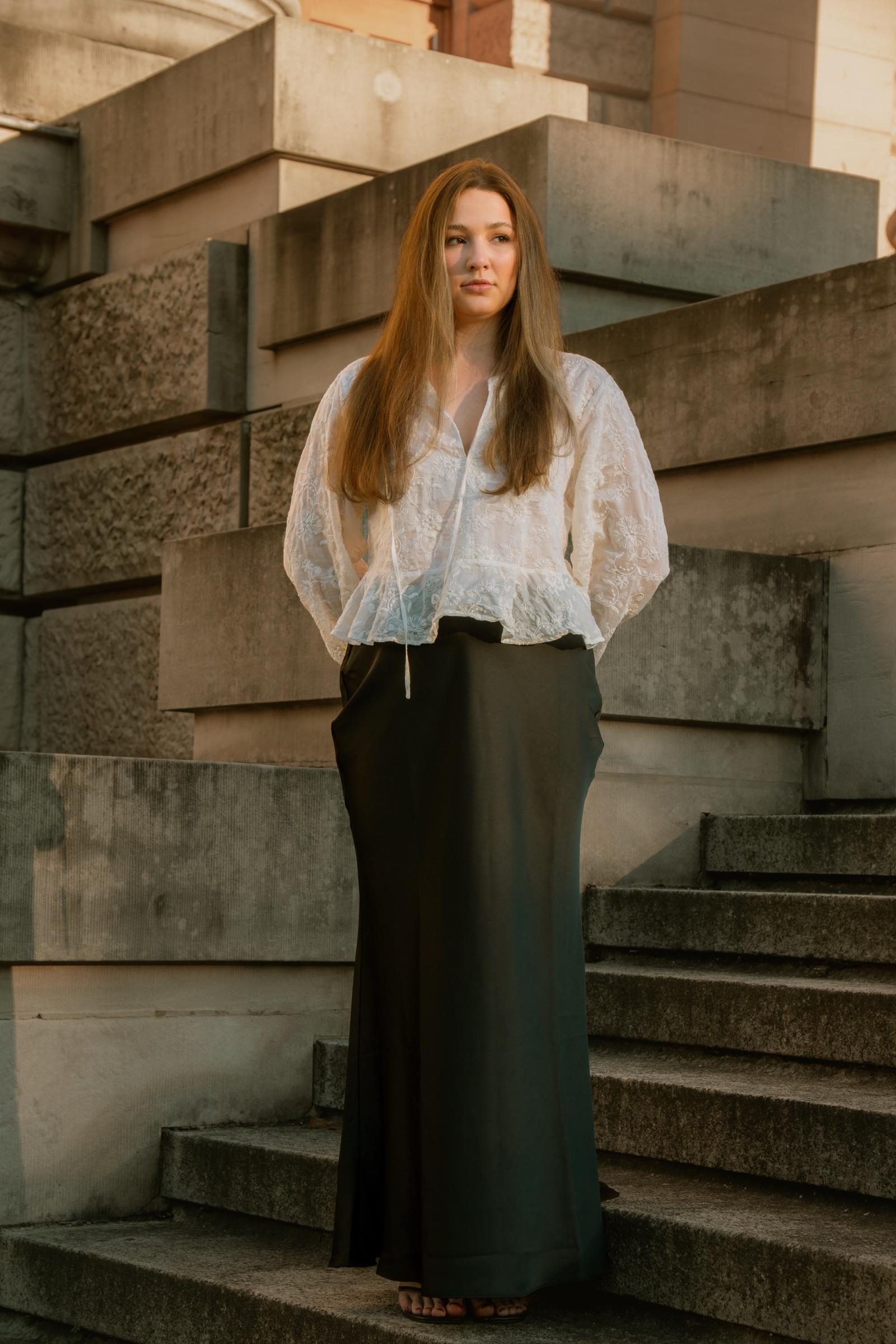 Portrait of a woman before stacked stone blocks at golden hour