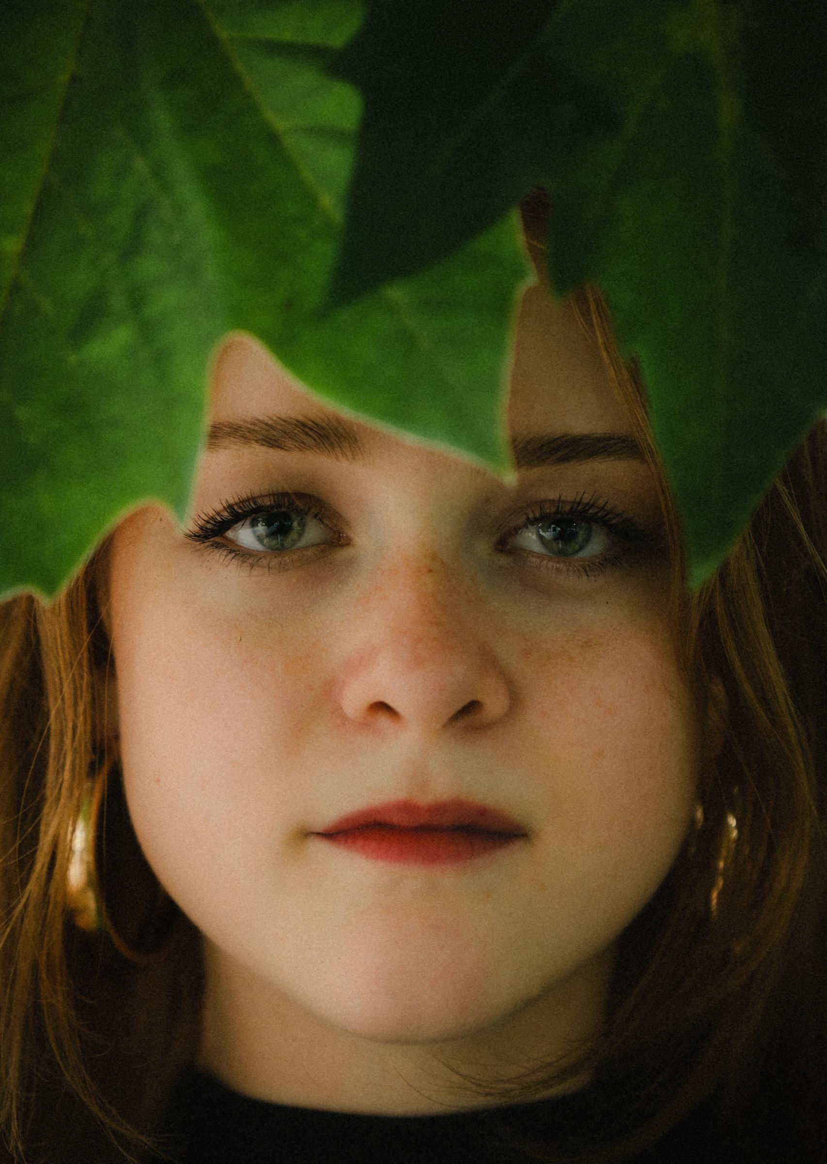 Portrait of a young woman framed by green leaves