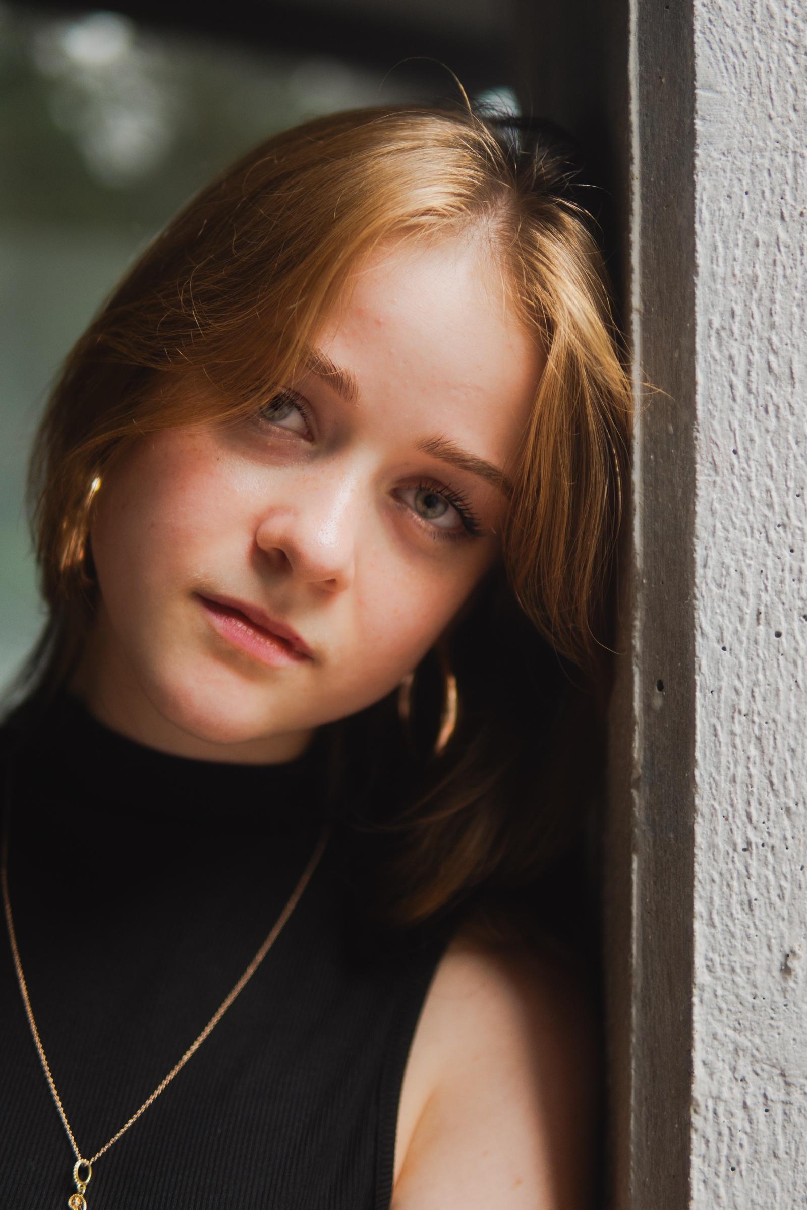 Moody portrait of a young woman leaning against a wall