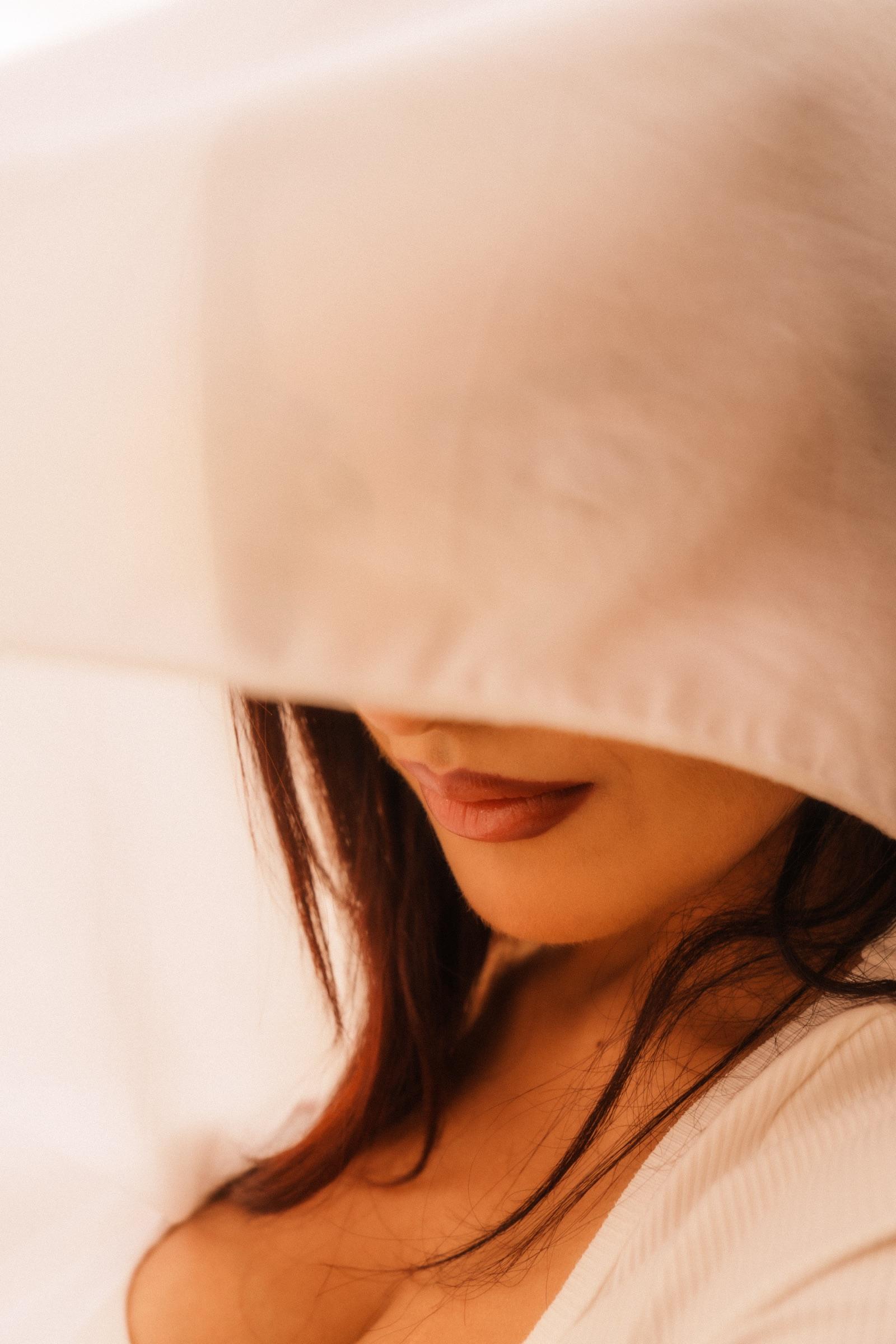 Editorial portrait with white fabric draped across the eyes