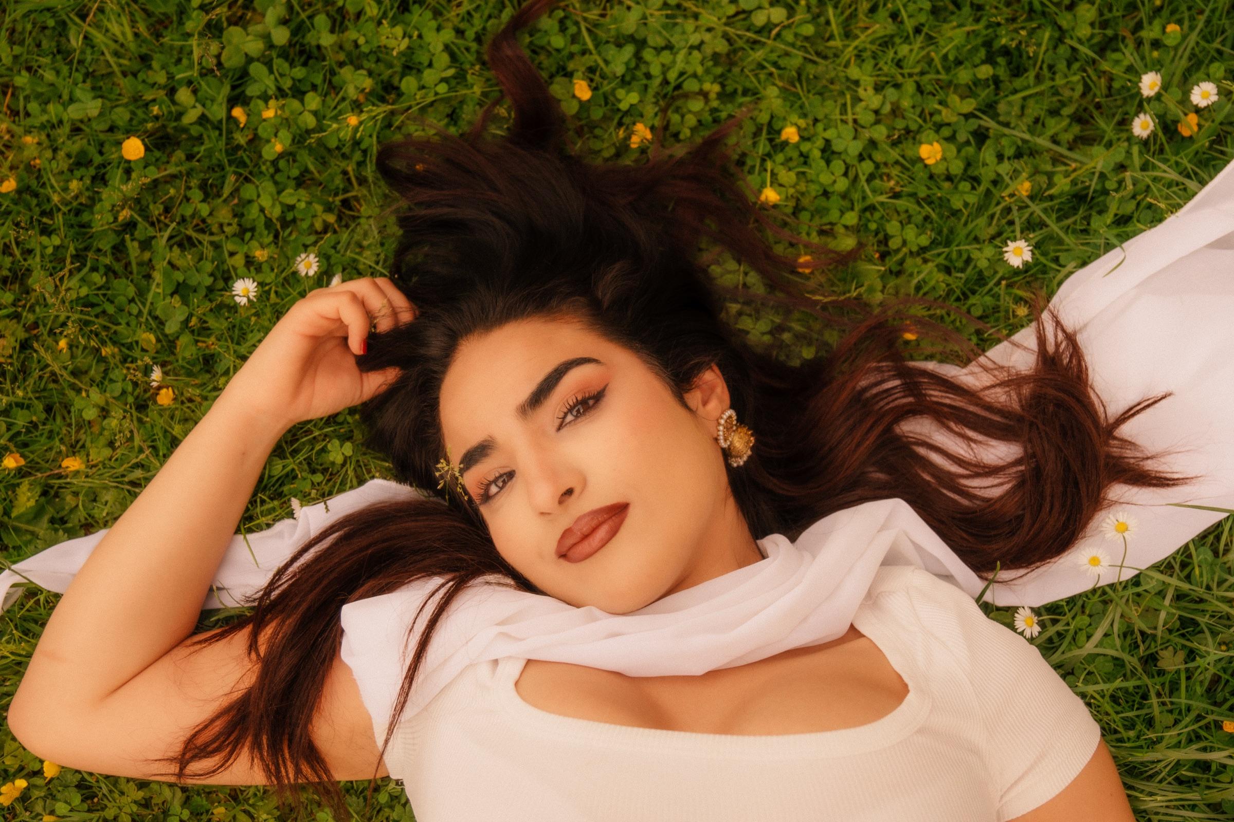 Portrait of a woman lying in grass scattered with daisies