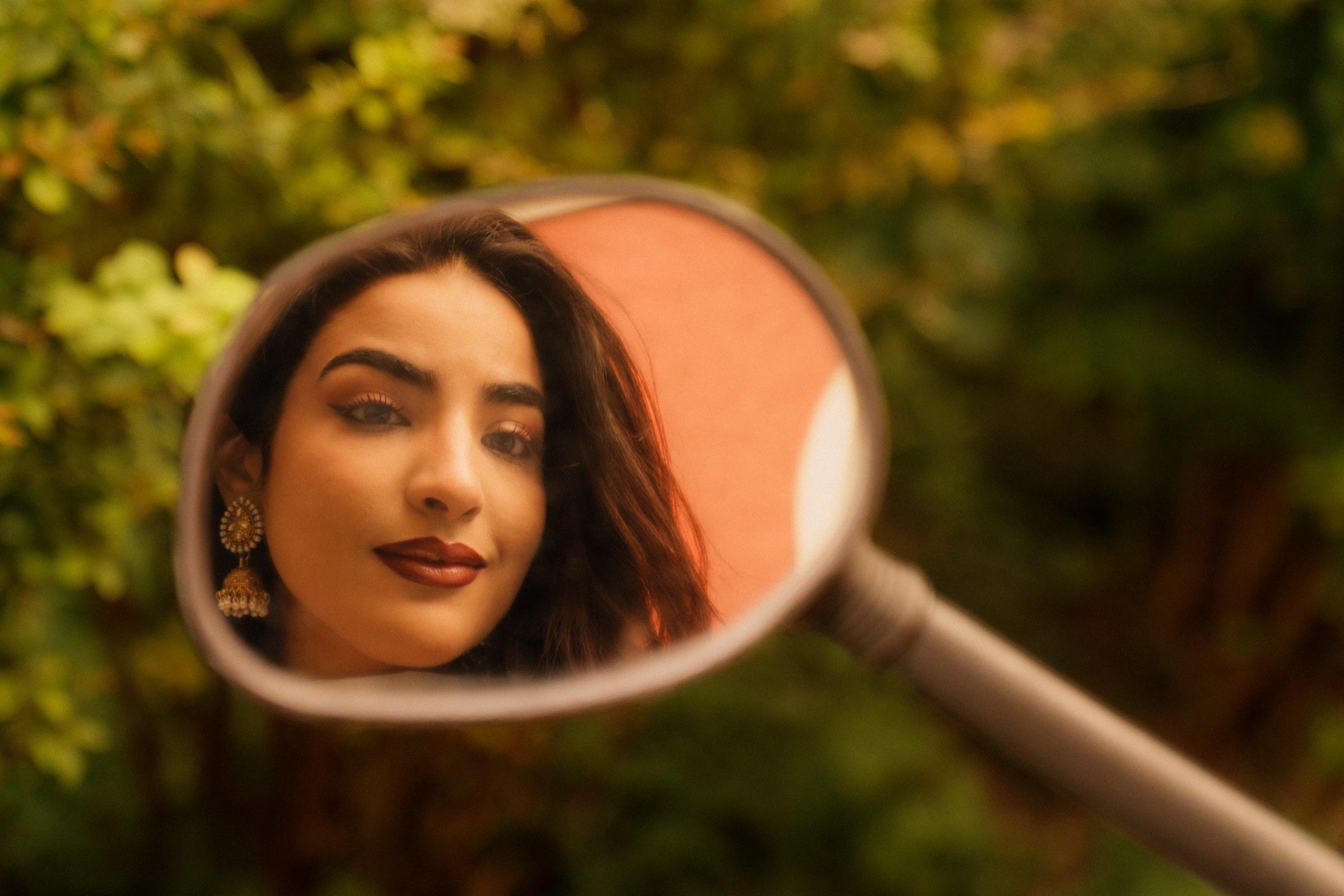 Portrait of a woman reflected in a round mirror amid greenery