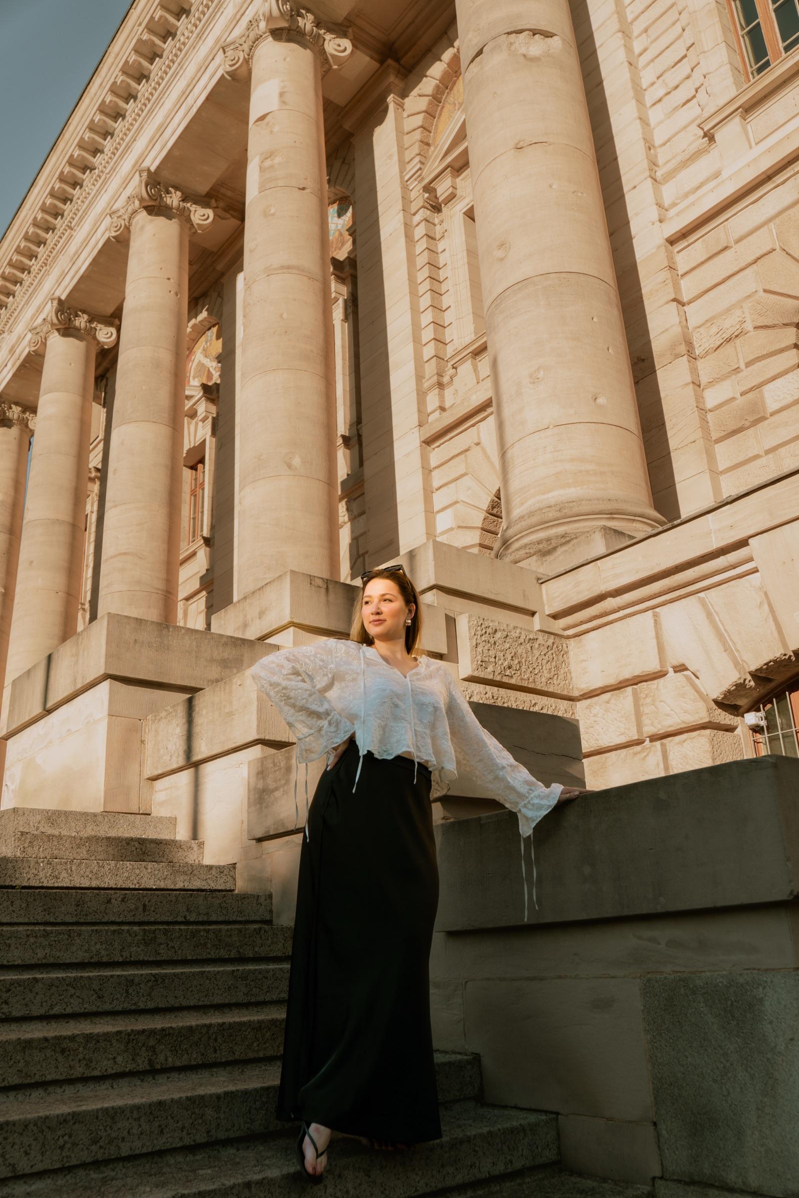 Editorial portrait on grand stone steps before classical columns